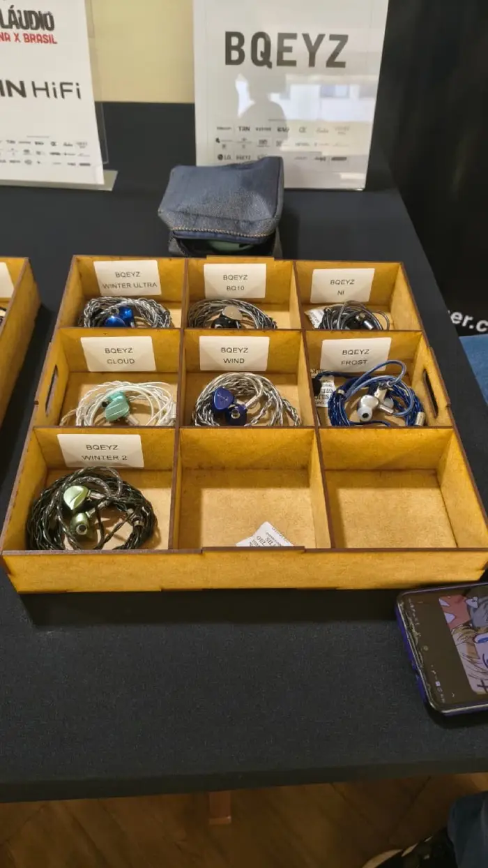 Caixas com cabos e IEMs organizados numa mesa de teste